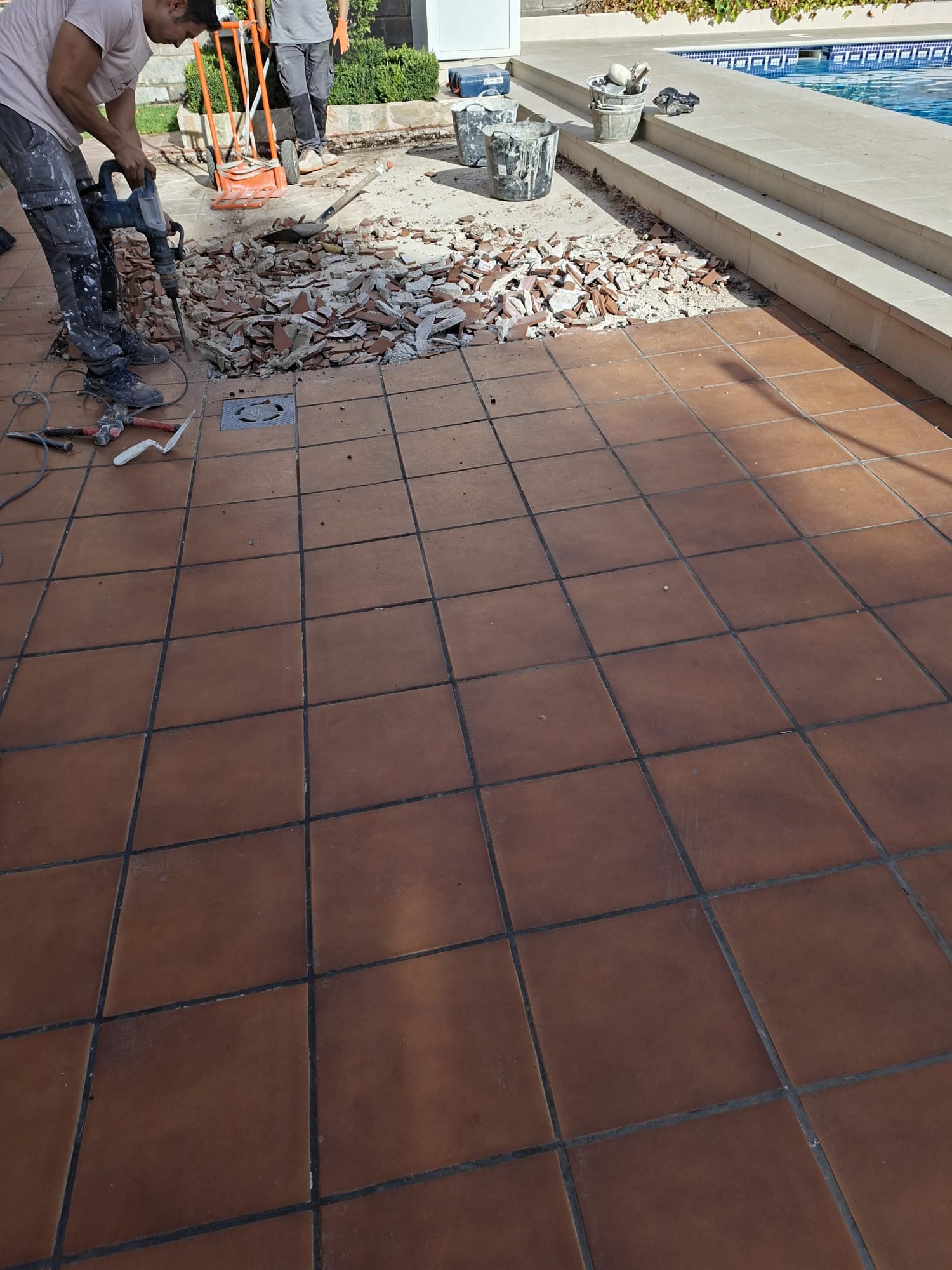 Terraza junto a piscina antes de la reforma, retirando el suelo antiguo